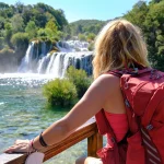 Touristin mit Rucksack bewundert den Wasserfall Skradinski Buk im Krka-Nationalpark. Tourismus, Kroatien, Sommer.